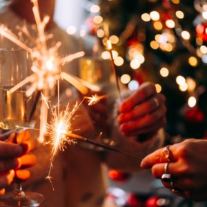 Friends celebrating Christmas or New Year eve party with Bengal lights and champagne.
