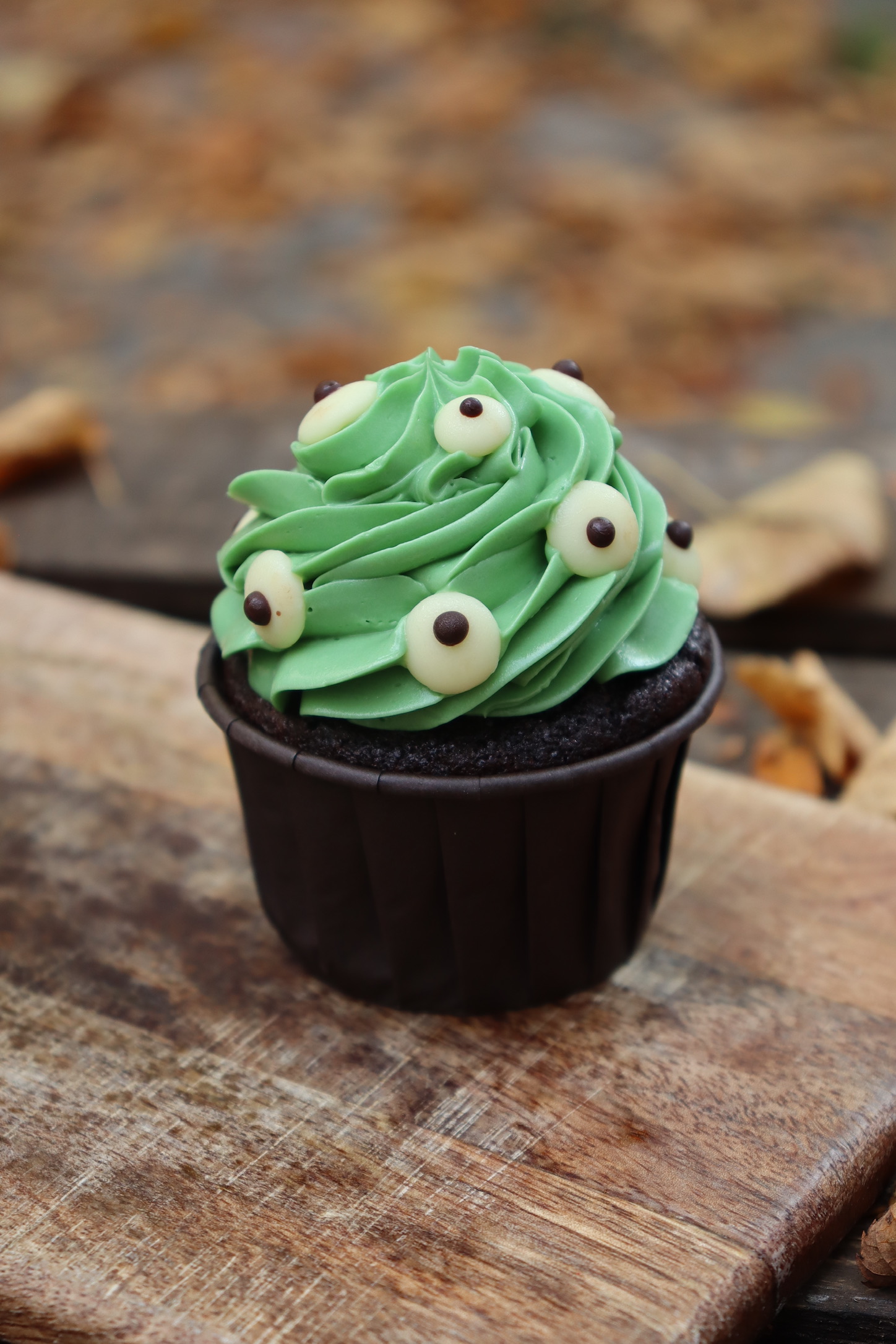 Halloween-Cupcake-Box von Malina Stories mit 12 handdekorierten Schokoladen-Cupcakes, gefüllt mit fruchtigem Himbeerkompott und verfeinert mit Vanille-Buttercreme in zwei gruseligen Halloween-Designs.