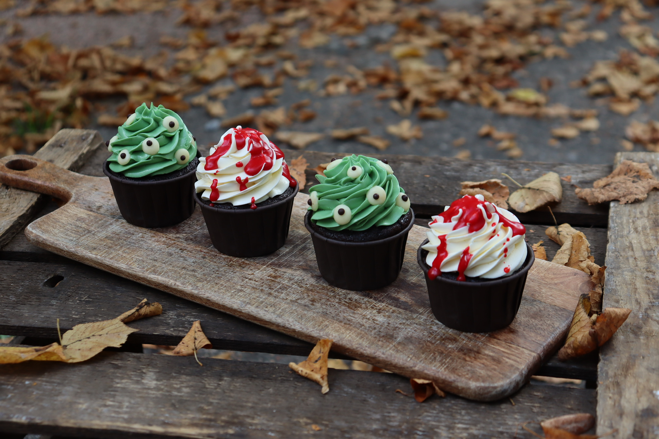 Halloween-Cupcake-Box von Malina Stories mit 4 handdekorierten Schokoladen-Cupcakes, gefüllt mit fruchtigem Himbeerkompott und verfeinert mit Vanille-Buttercreme in zwei gruseligen Halloween-Designs.